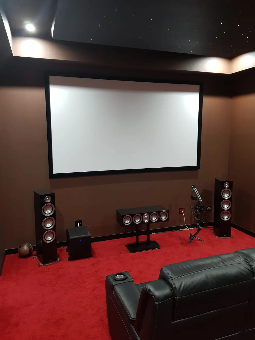 Dedicated home theatre with red carpet, floor-standing speakers and recliners
